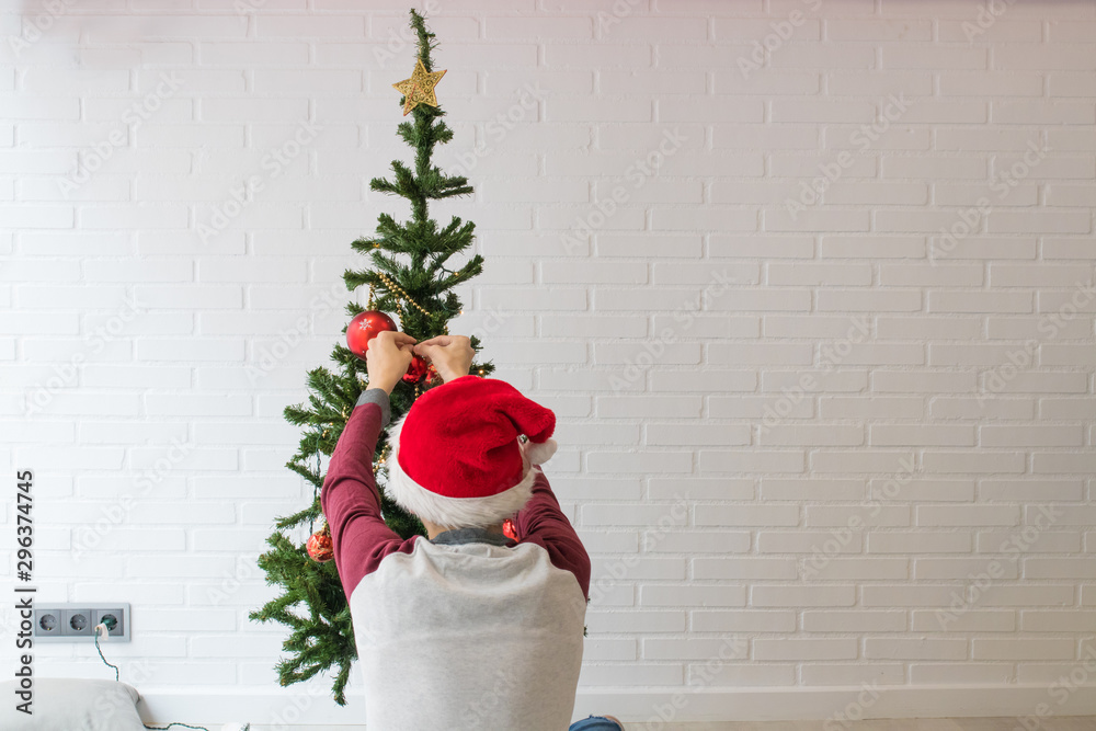 Fototapeta premium boy with his back at home decorating the christmas tree