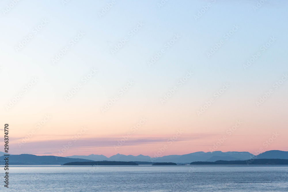 Scenic view of sea against sky during sunset with blue mountains
