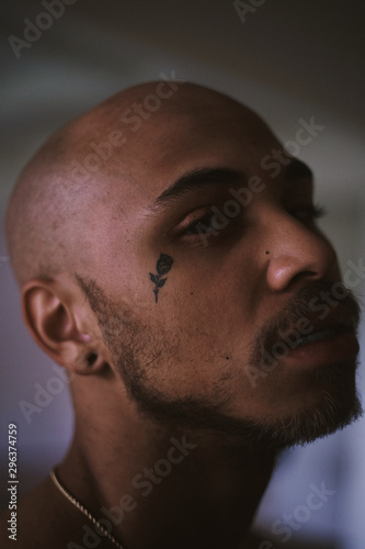 Close up view of bald bearded man with rose tattoo on cheek