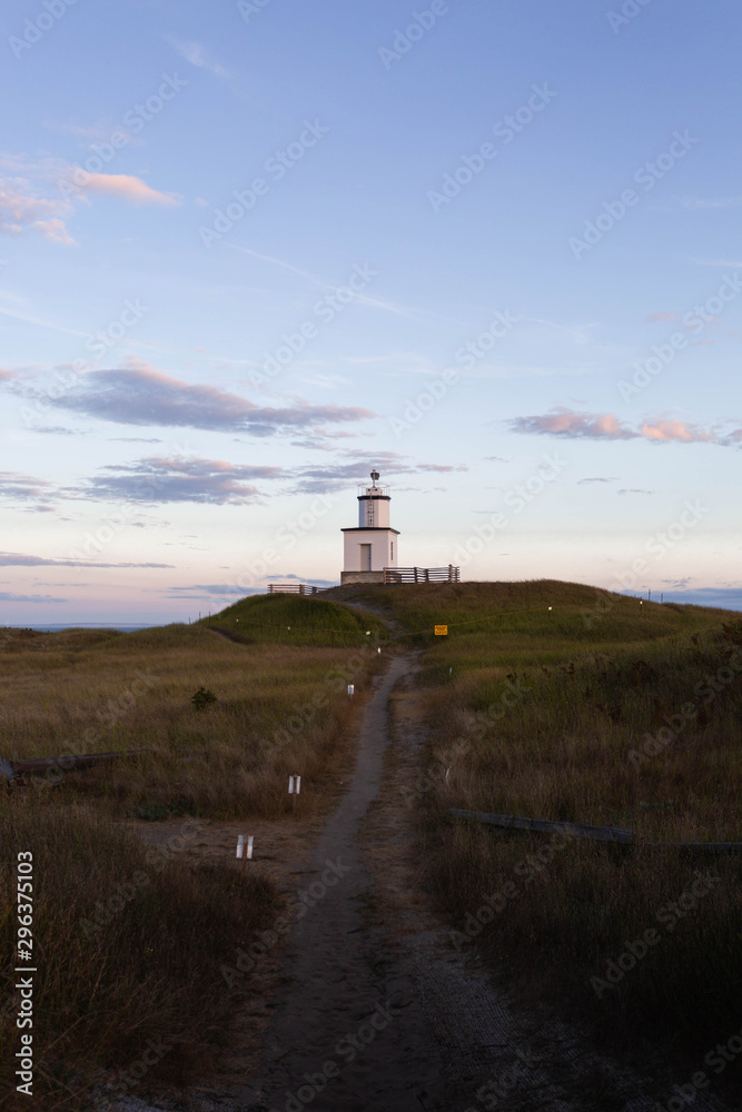 Scenic view of path leading to a lighthouse against cloudy sunset sky Scenic view of path leading to a lighthouse against cloudy sunset sky