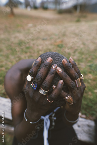 Close up of man holding ringed hands on head