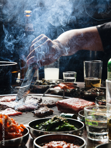 Close up of man preparing meat on small barbecue grill photo