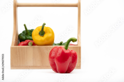 Red, Yellow, Green Peppers in wooden basket  on white background.