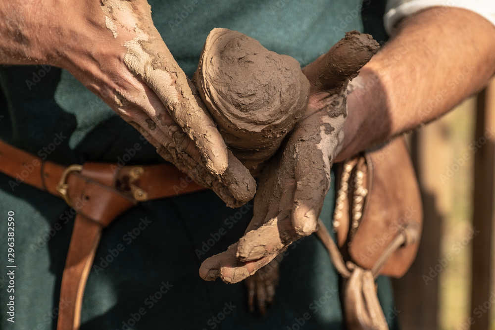 Reconstruction of old crafts.An artisan wrinkles clay to create pottery. Holds a lump of clay in his hand. Teaches pottery art. Shows how to sculpt. Dressed in an old outfit. Twists the clay. Workshop
