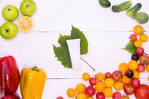 Care cosmetics from natural fruits and vegetables. White jar of cream vegetables around top view. White wood background. The concept of vegetarianism and detox for the skin.