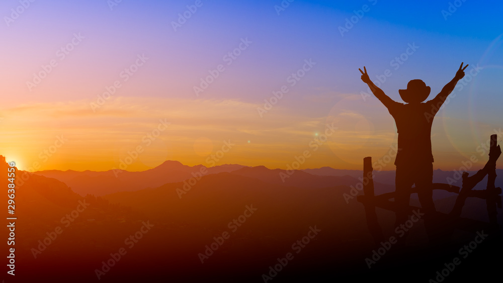 silhouette picture backpacker man show two finger victory sign with lens flare sunset and mountain background twilight time copy space.