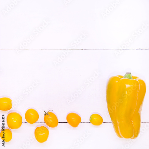 Concept yellow vegetables on a white background top view. White wood texture. Yellow peppers and tomatoes and lemon. Square frame made of vegetables. Proper nutrition. Detox vegetarianism and diet