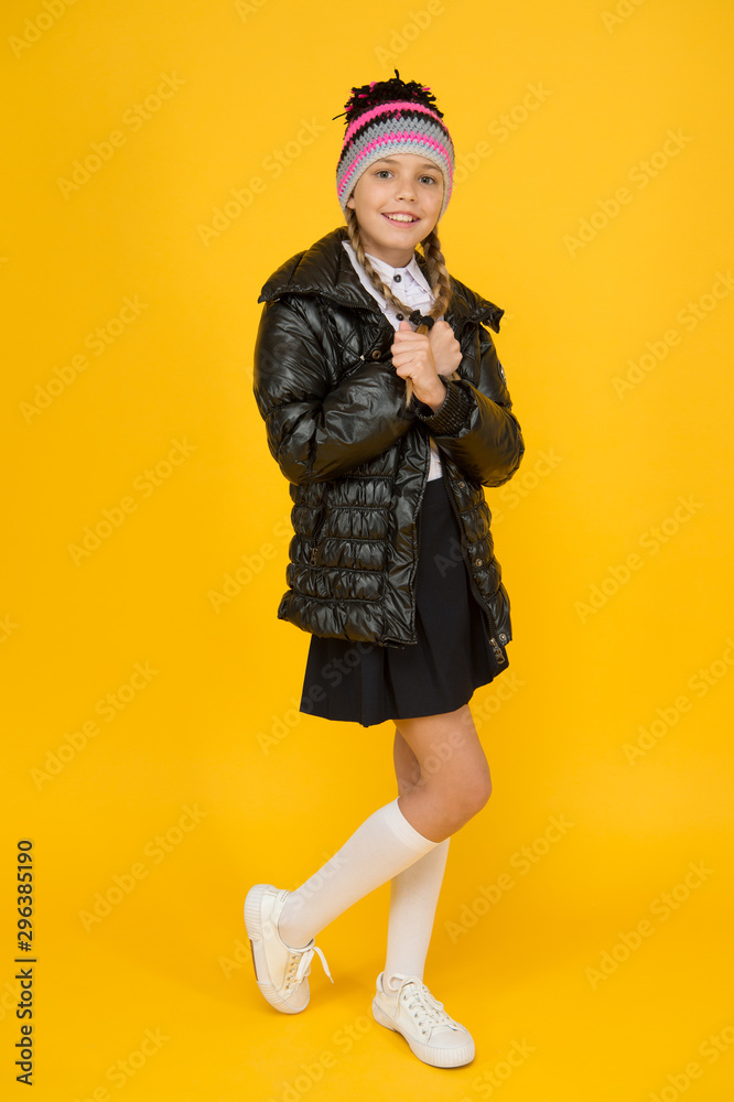 Fancy little child. Fashion shop. Girl wear knitted hat and down jacket yellow background. Fashion concept. Warm clothing. Buy clothes for school season. Schoolgirl fashion outfit. Fall autumn winter Fancy little child. Fashion shop. Girl wear knitted hat and down jacket yellow background. Fashion concept. Warm clothing. Buy clothes for school season. Schoolgirl fashion outfit. Fall autumn winter