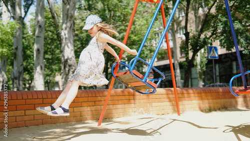 Beautiful little girl jumping from a swing. The concept of summer holidays.