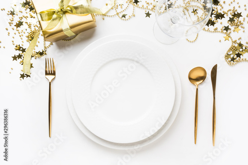 Christmas table setting with golden dishware, silverware on white background. Top view.