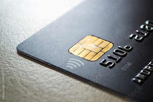 Black credit card with chip and contactless pay technology close-up. Low key shot with old credit card. photo