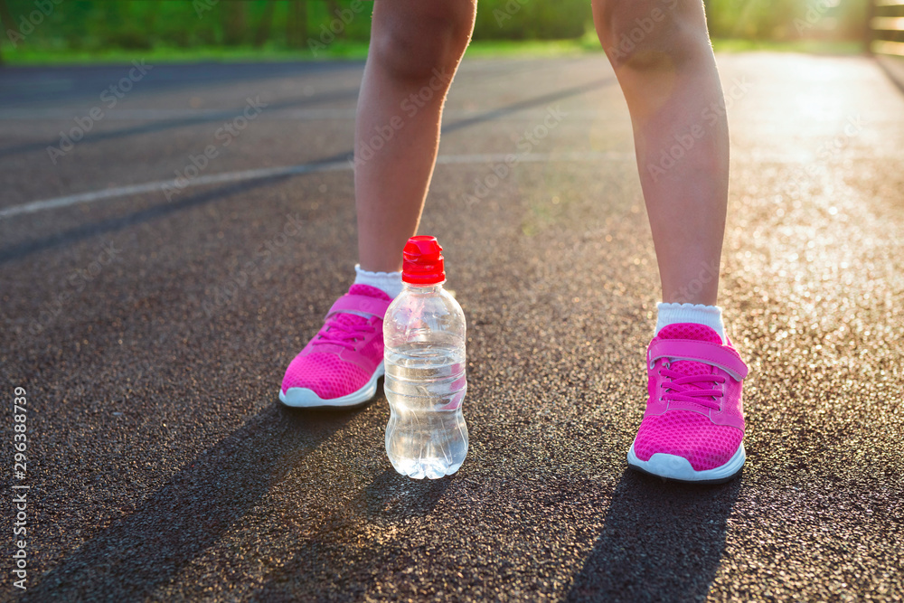 Bottle of pure water and legs close-up. Healthy lifestyle and sport concepts.
