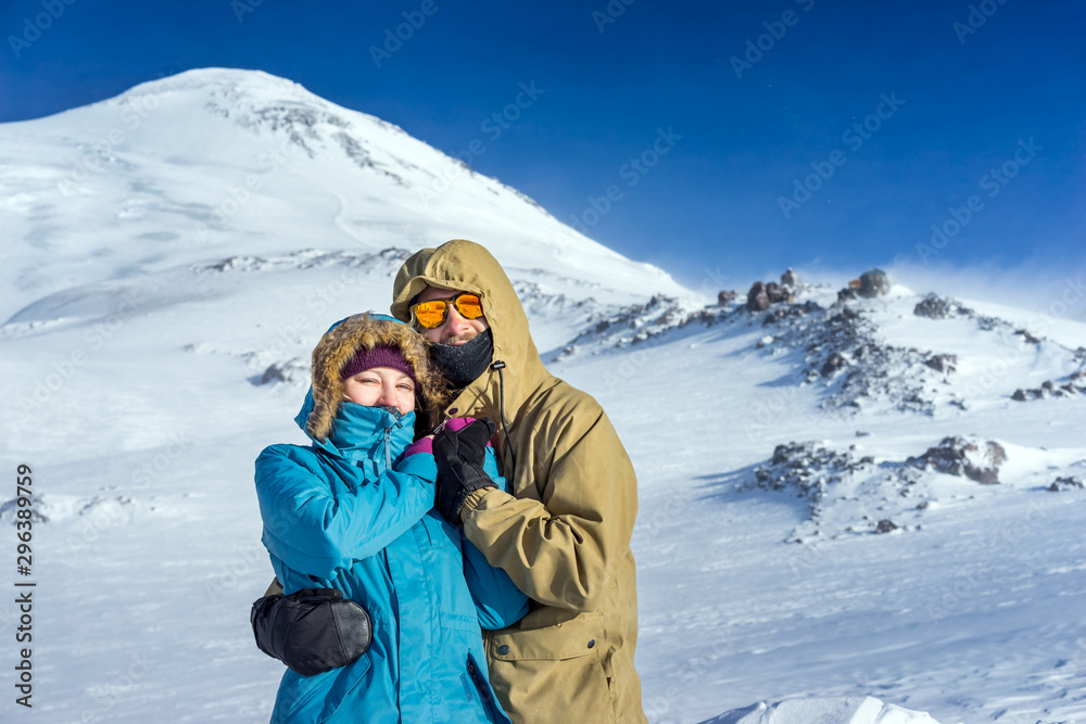 Happy young couple snowboarders on the background high mountains on the winter resort