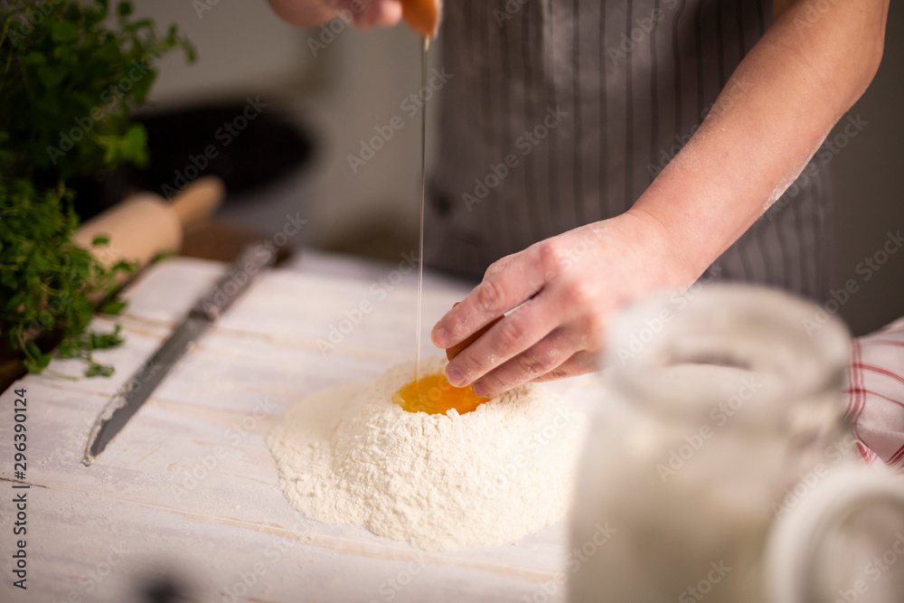 A woman sticks an egg into flour, prepares homemade pasta dough