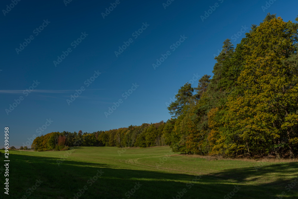 Color autumn meadow and forests with blue sky in Kokorinsko area in Bohemia