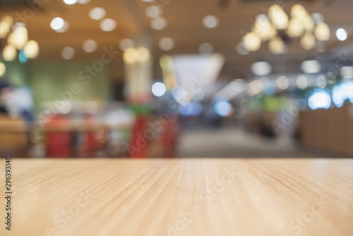 Empty light colored wood table top and blur of food court restaurant background selective focus. For montage product display.