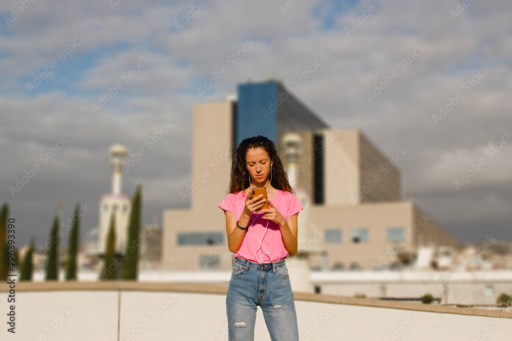young woman texting a message on the phone on a urban environment