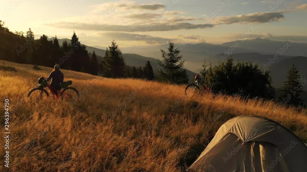 4k drone clip with two mountain bikes and a tent on a mountain meadow at sunrise in autumn season. Adventure cycling concept.