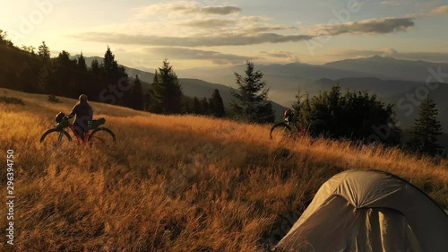 4k drone clip with two mountain bikes and a tent on a mountain meadow at sunrise in autumn season. Adventure cycling concept.