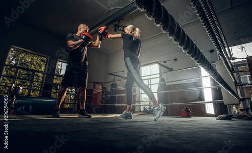 Boxing trainer and his new student have a sparring on the ring wearing boxing gloves. photo