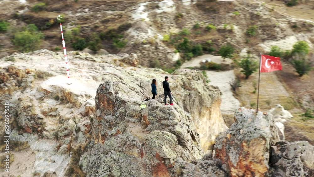 Rotational drone shot of couple standing on a rocky ridge with the Turkey flag appearing in frame Rotational drone shot of couple standing on a rocky ridge with the Turkey flag appearing in frame