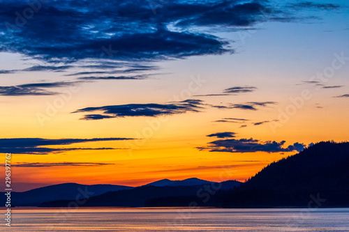 Fototapeta Naklejka Na Ścianę i Meble -  Orange Setting Sunset, Mountains silhouetted, Ocean