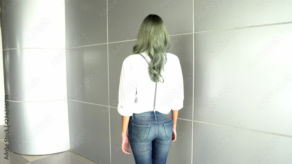 Fashion Model poses along Silver wall. Asian Teenager Womam in Green coloring Hair white shirt necktie jean pants walks and move forward and look smile at camera, 4k video gimbal Fashion Model poses along Silver wall. Asian Teenager Womam in Green coloring Hair white shirt necktie jean pants walks and move forward and look smile at camera, 4k video gimbal