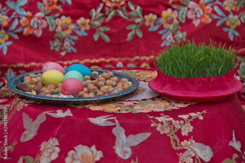 Novruz symbol on xoncha on white background Azerbaijan holiday . Green semeni . There are colored eggs, hazelnuts, dates, and peanuts in the cabin. photo