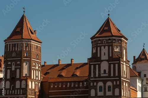 View of the Belarusian Mir castle complex made of red brick against a bright blue sky on a sunny cloudless day