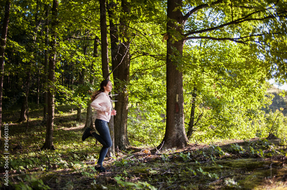 Young girl jogging in the woods on a sunny morning. Young girl jogging in the woods on a sunny morning.