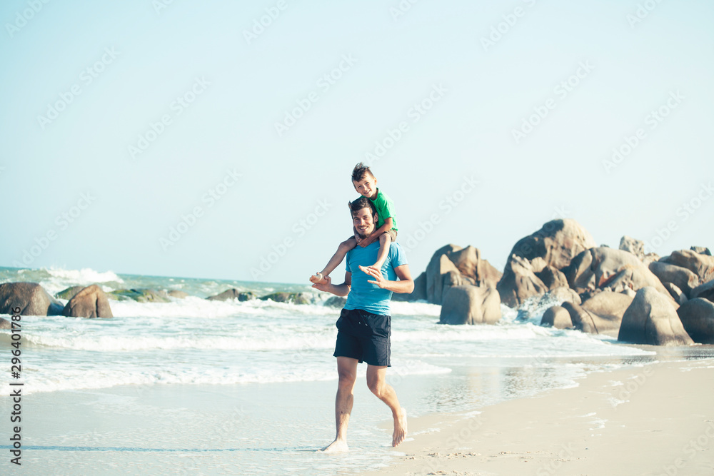 happy family on beach playing, father with son walking sea coast, rocks behind smiling taking vacation happy family on beach playing, father with son walking sea coast, rocks behind smiling taking vacation
