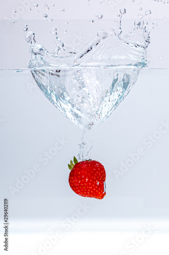 strawberry falling in water splash on white background in portrait	