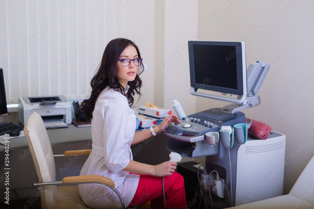 brunette girl in glasses. Doctor sits near the ultrasound diagnostic apparatus. brunette girl in glasses. Doctor sits near the ultrasound diagnostic apparatus.