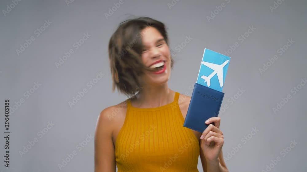 travel, tourism and vacation concept - happy laughing young woman in mustard yellow top with air ticket and passport over grey background travel, tourism and vacation concept - happy laughing young woman in mustard yellow top with air ticket and passport over grey background