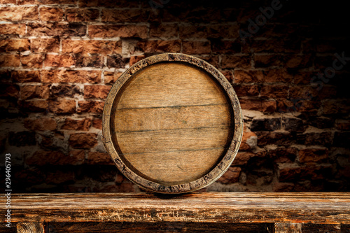 Old wooden wine barrelwith table board and brick wall background.