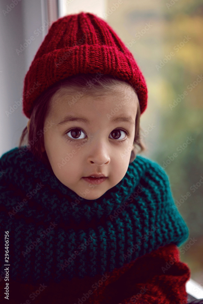 boy child in red knitted sweater and hat sitting on the window boy child in red knitted sweater and hat sitting on the window
