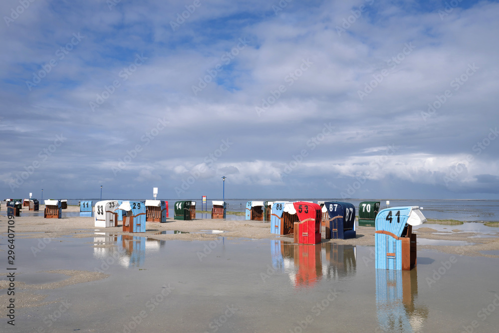Wattenmeer und Strand von Neuharlingersiel an der Nordsee nach heftigem Regen mit Strandkörben und Pfützen und Wasserlachen - Stockfoto