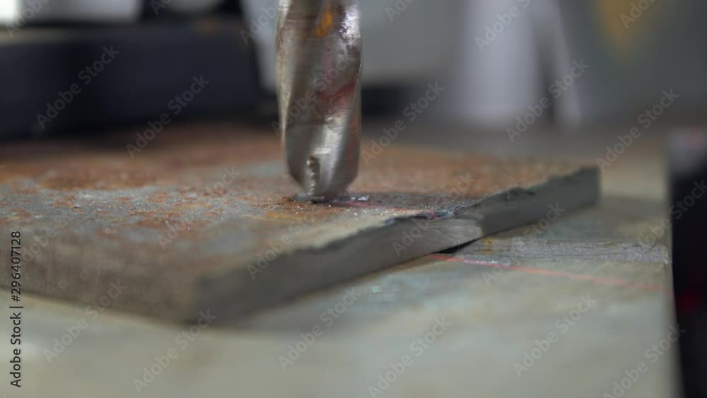 close up of drill bit in drilling machine makes hole in metal sheet close up of drill bit in drilling machine makes hole in metal sheet