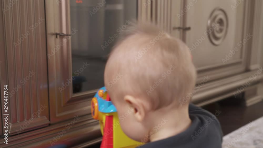 Active little boy crawling with a colorful toy trolley in stylish interior living room. Happy childhood moments. Nursing child concept. Active little boy crawling with a colorful toy trolley in stylish interior living room. Happy childhood moments. Nursing child concept.