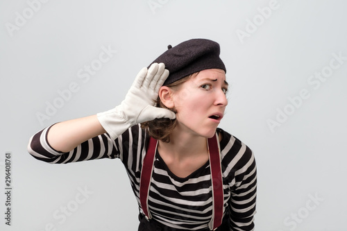 Young caucasian mime woman doing a hearing gesture. Studio shot