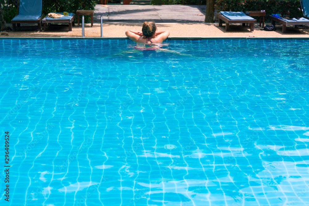 Young woman relaxes in the swimming pool.