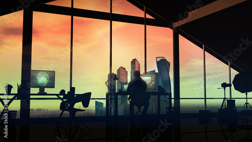 A photographer in his studio with large windows on a sunset background.