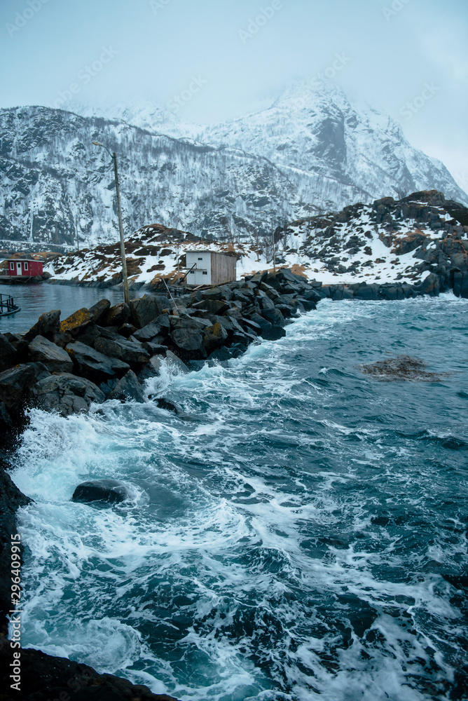 Fototapeta premium Norway. Stone breakwater that separates the ocean from fishing town.