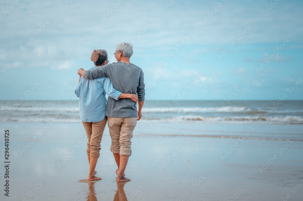 Senior couples walking on the beach at sunny day, plan life insurance with the concept of happy retirement.