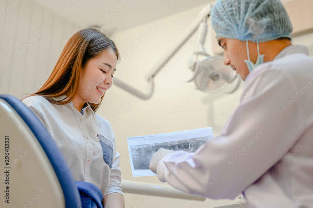 The dentist is looking at the patient's dental x-ray results for an effective treatment and improves the patient's dental health and a bright smile.. The dentist is looking at the patient's dental x-ray results for an effective treatment and improves the patient's dental health and a bright smile..