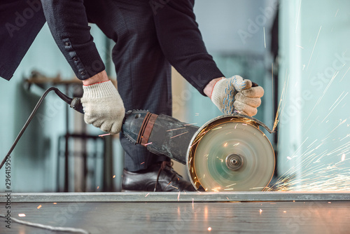 Fotografia, Obraz Man is cutting a metal by angle grinder saw.