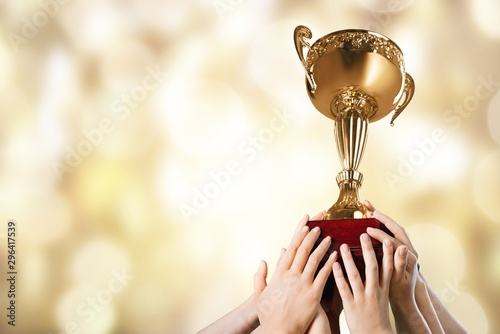 Hand holding golden trophy on background