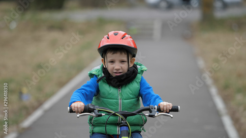 Little boy riding bicycle on alley, kid with protection helmet learning