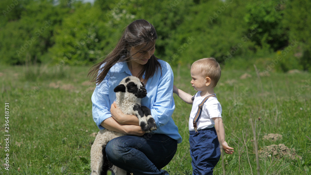 Baby child and mother portrait, parent holding little lamb, learn to love animal