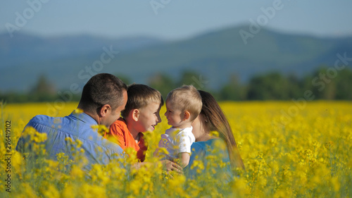 Happy family in blossom rape field, children play, kiss and embrace, smiling © MEDIAIMAG